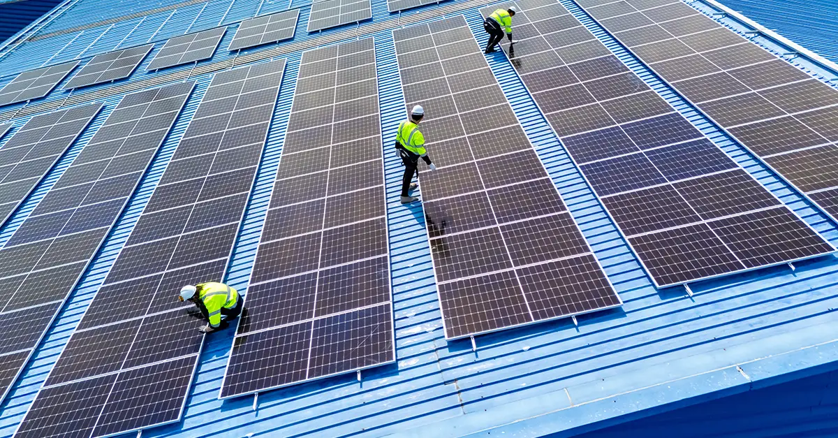 Construction workers installing rooftop solar panels on a commercial building, representing operational carbon reduction under the UK Net Zero Carbon Buildings Standard